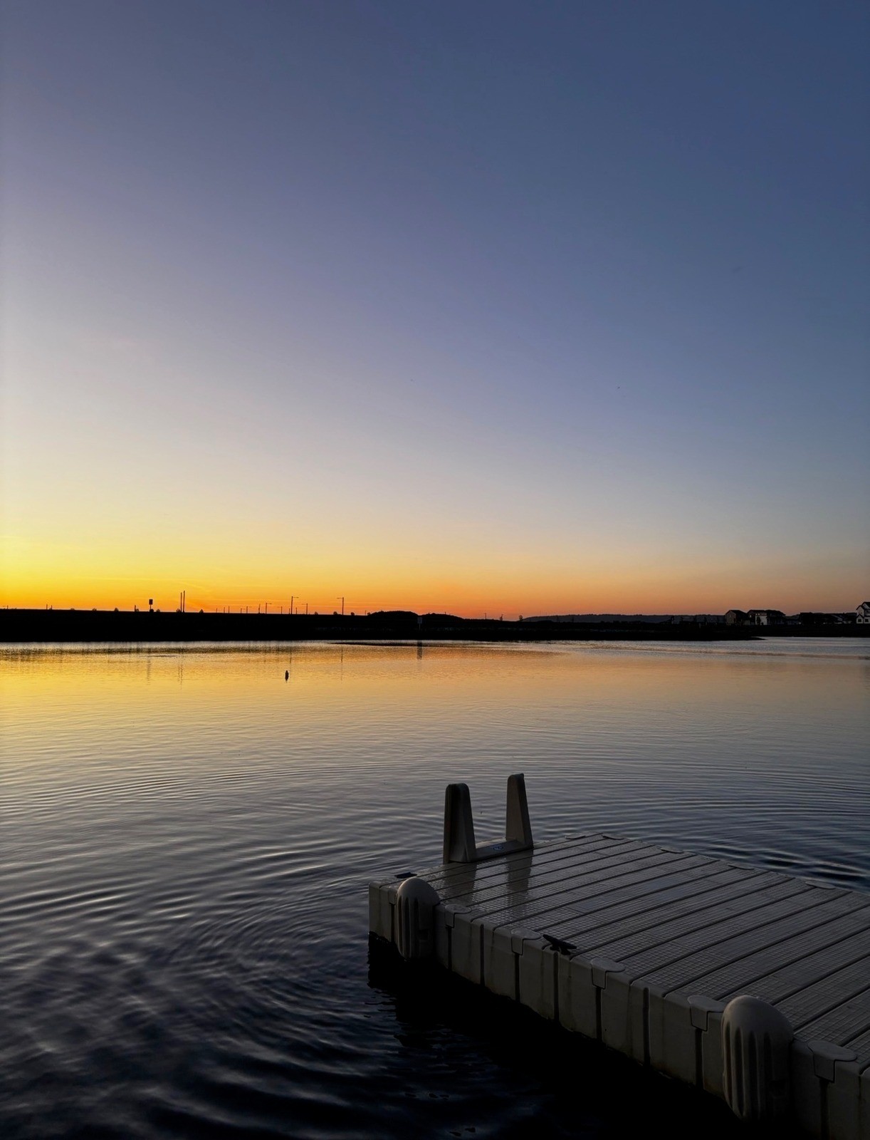 Sunset over a calm lake with a floating dock